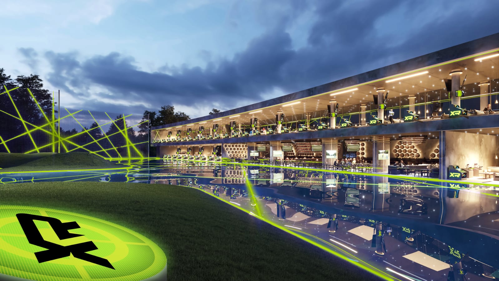 Two levels of open hitting bays facing a floodlit range at dusk, with green shot-tracer lines arcing across the outfield and perimeter netting behind.